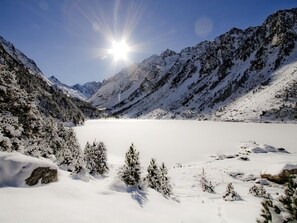 A snow-covered mountainous landscape with a clear sky and sunlight.