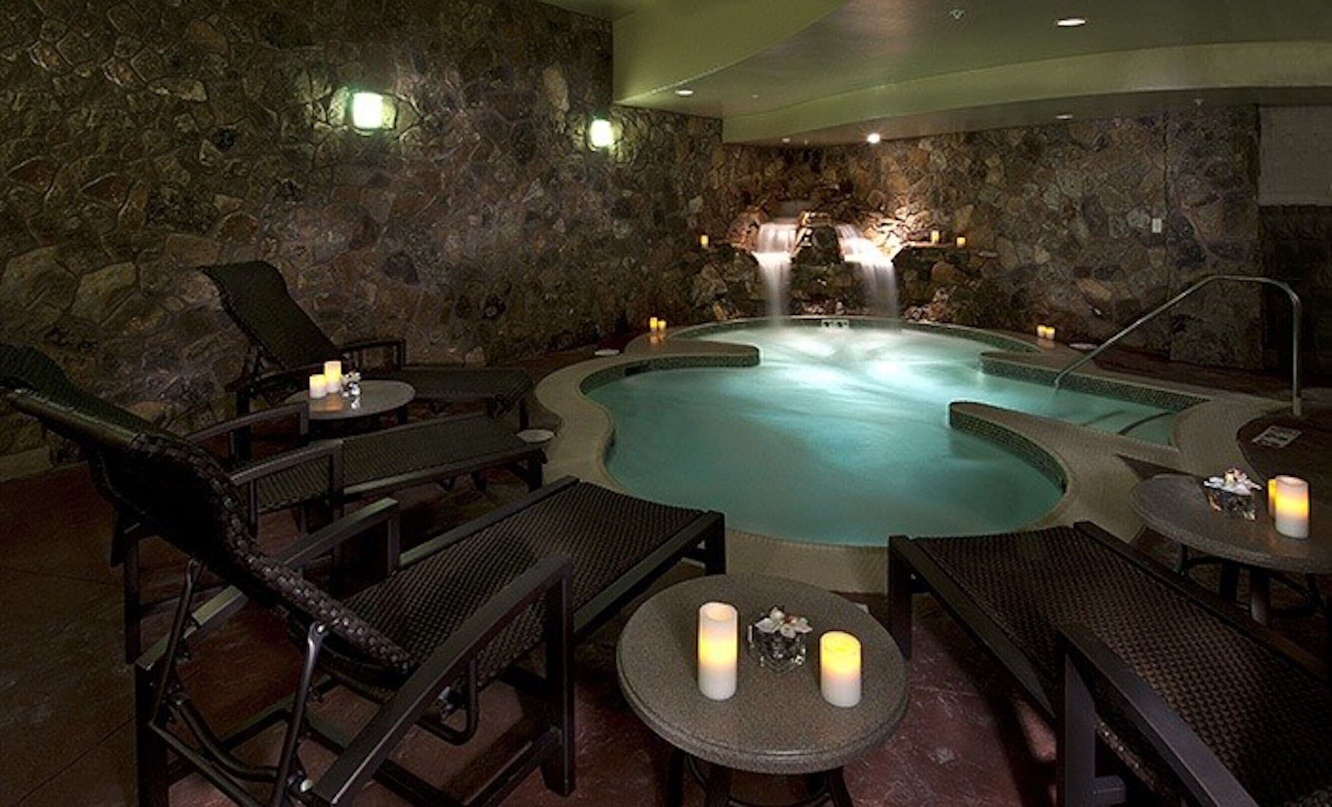 Ein Wellnessbereich mit Whirlpool, Liegestühlen und Kerzen.