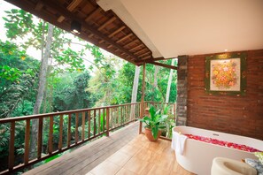 A balcony with a wooden railing overlooking a lush forest. - Apple Resort Retreat Spa (Tabanan)