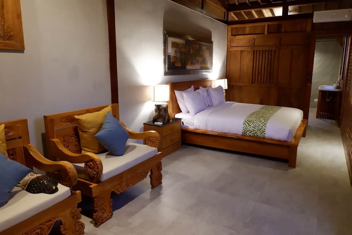 A bedroom with a wooden bed, a wooden sofa, and a nightstand with a lamp.