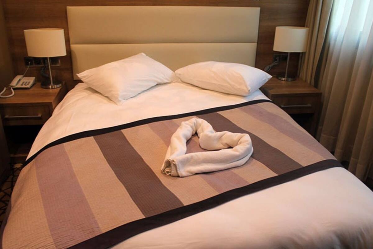 A hotel room with a bed, two bedside lamps, and a telephone on the nightstand.