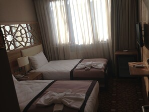 A hotel room with two beds, a TV, a desk, and a window with curtains. - Prens Hotel (Istanbul)
