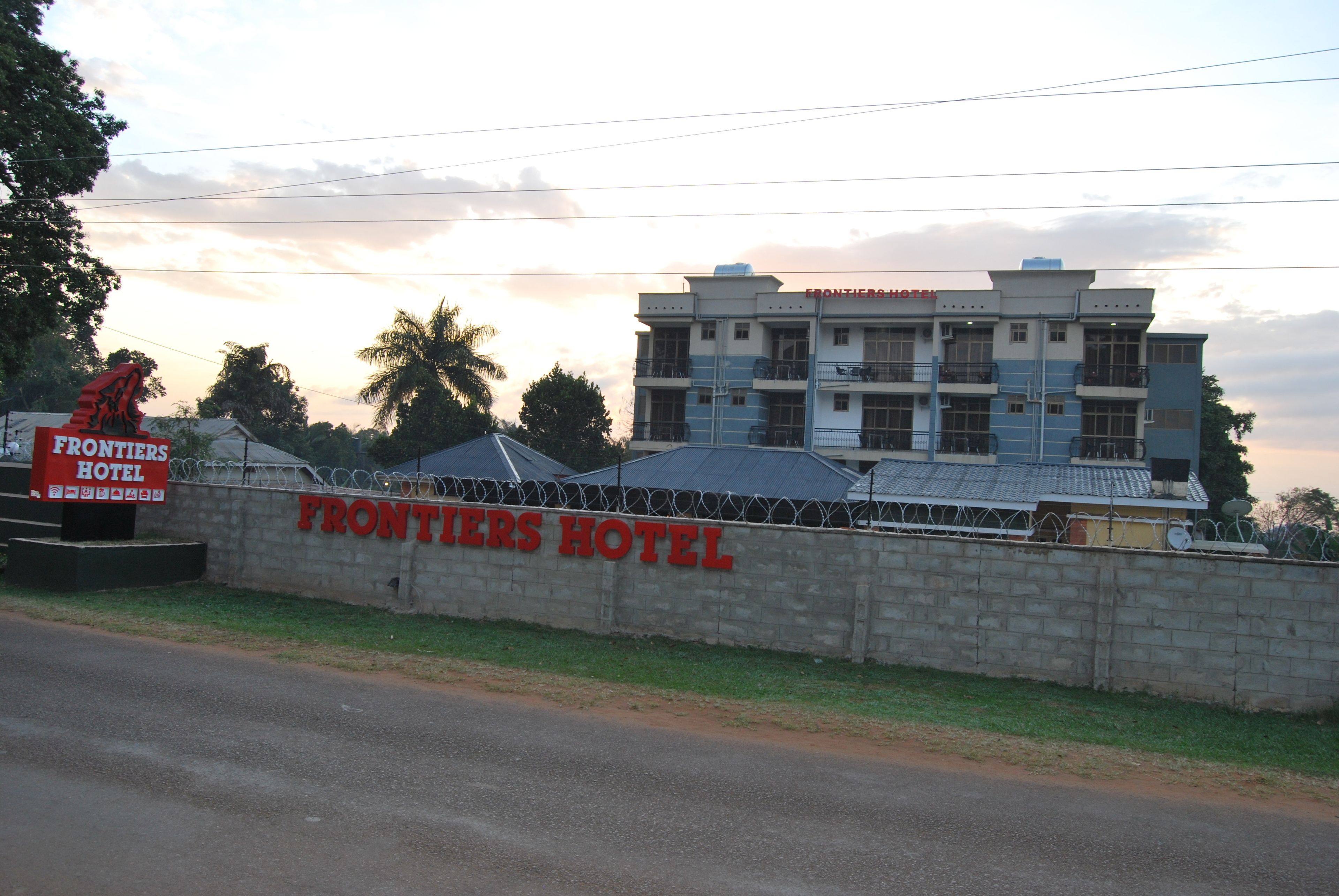 A hotel named "Frontiers Hotel" with a stone wall and barbed wire fence.