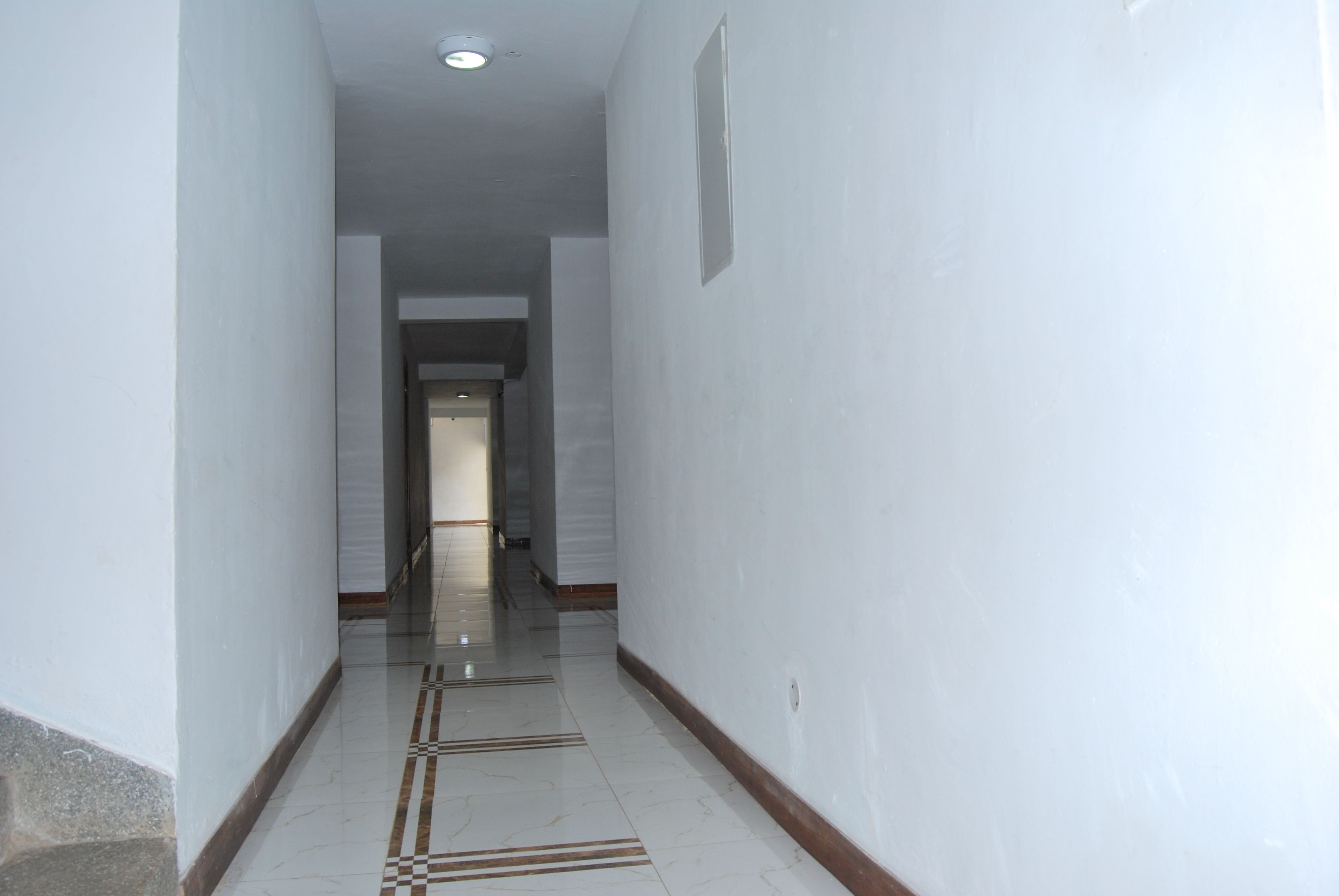 A narrow hallway with white walls and a tiled floor.