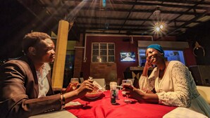 A dining area with a red tablecloth, a television mounted on the wall, and a ceiling with exposed beams. - Frontiers Hotel Entebbe (Entebbe)