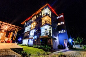 Un hotel de varios pisos con balcones y una entrada bien iluminada.
