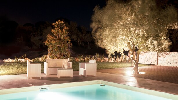 Piscina com espreguiçadeiras e uma árvore.