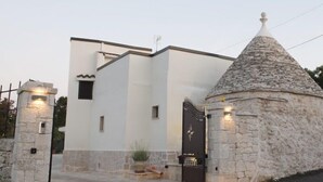 Um edifício com fachada branca, uma torre de pedra e um portão.