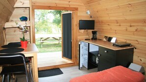Ein gemütliches Holzhaus mit Essbereich, Schreibtisch inklusive Computer und einem Bett.