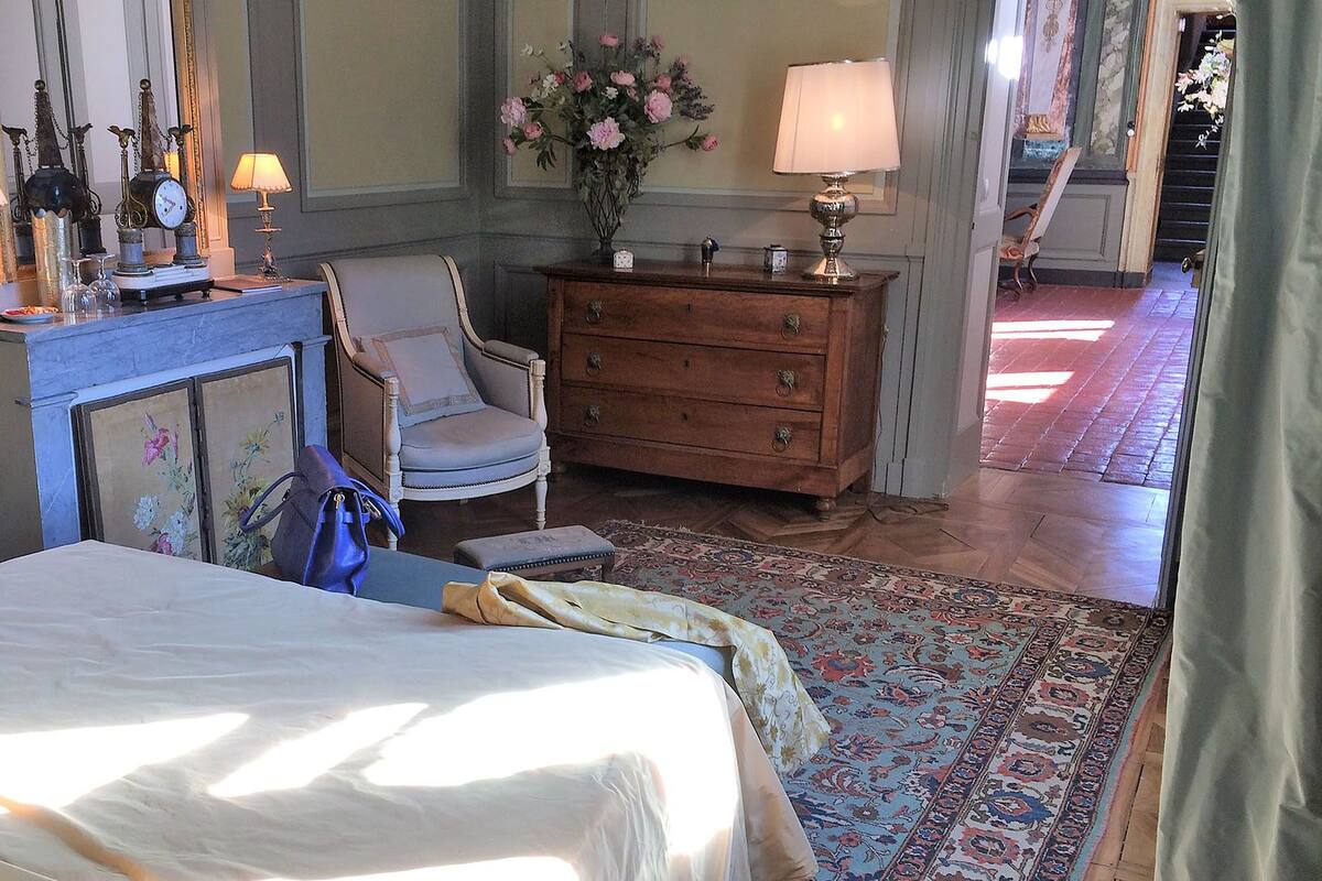 A bedroom with a bed, a dresser, a chair, and a mirror.