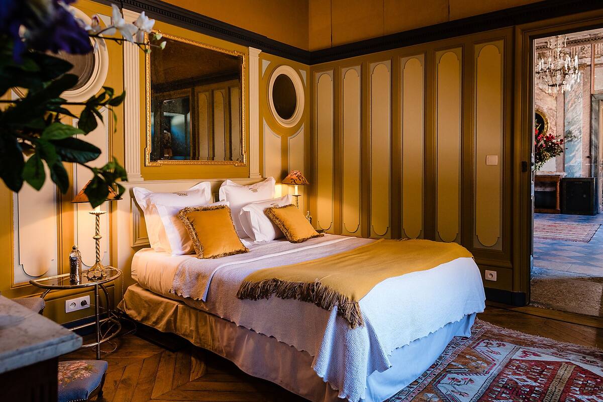 A well-appointed bedroom with a large bed, a mirror, and a chandelier.