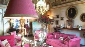 A room with a grand chandelier, a piano, and a pink sofa. - Château de Saint Trys (Anse)