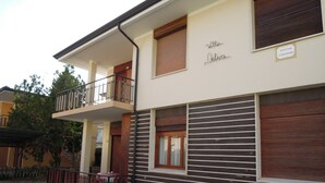 A two-story building with a balcony, a sign with the name 'Villa Delara', and a window with a wooden shutter. - Villa Dilva (San Michele al Tagliamento)