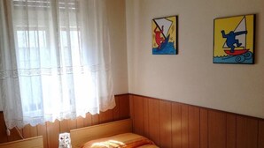A bedroom with two single beds, a wooden headboard, a window with sheer curtains, and two wall art pieces depicting sailing scenes. - Villa Dilva (San Michele al Tagliamento)