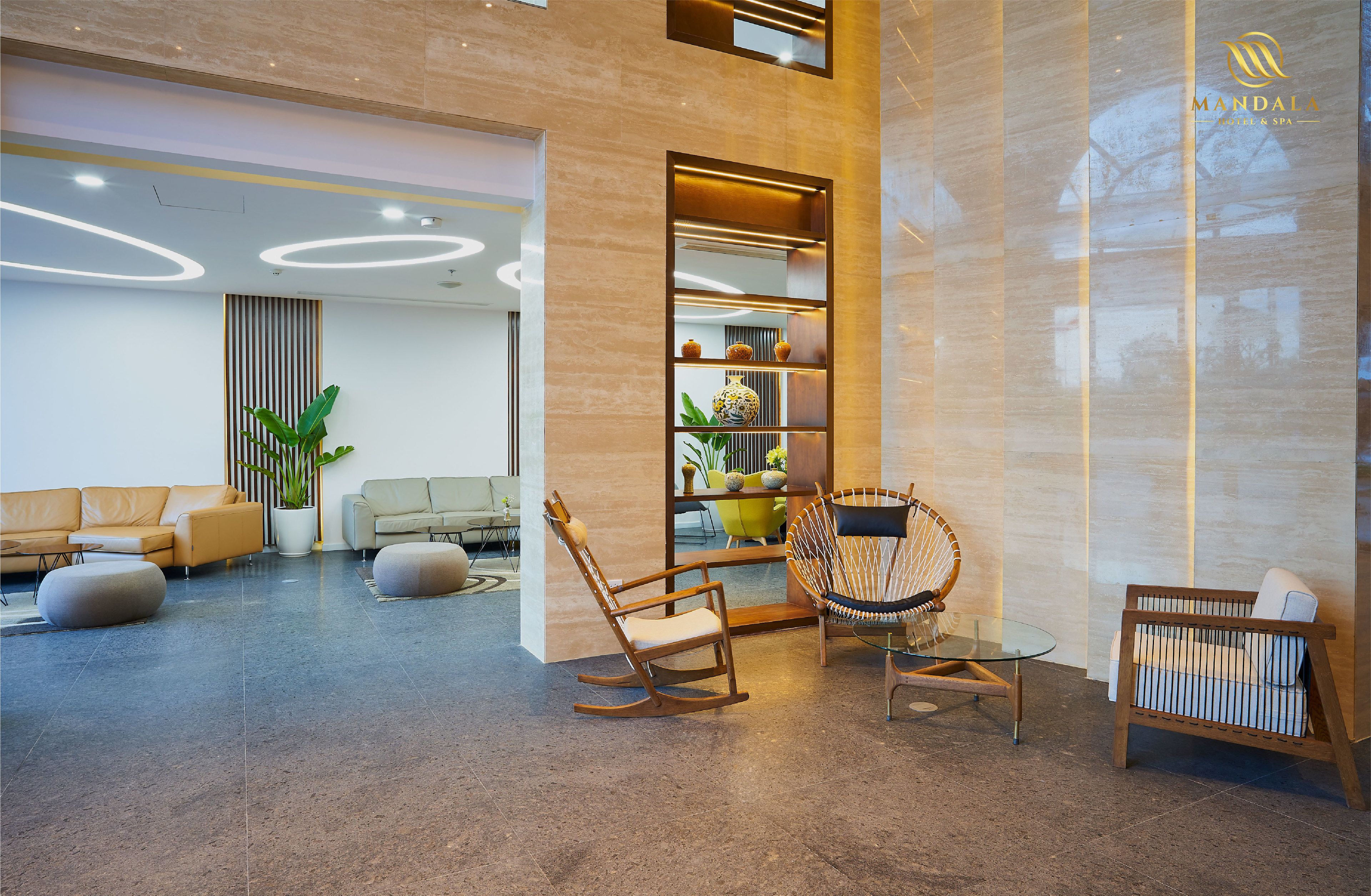 A modern lobby with a seating area, a glass table, and a decorative shelf.