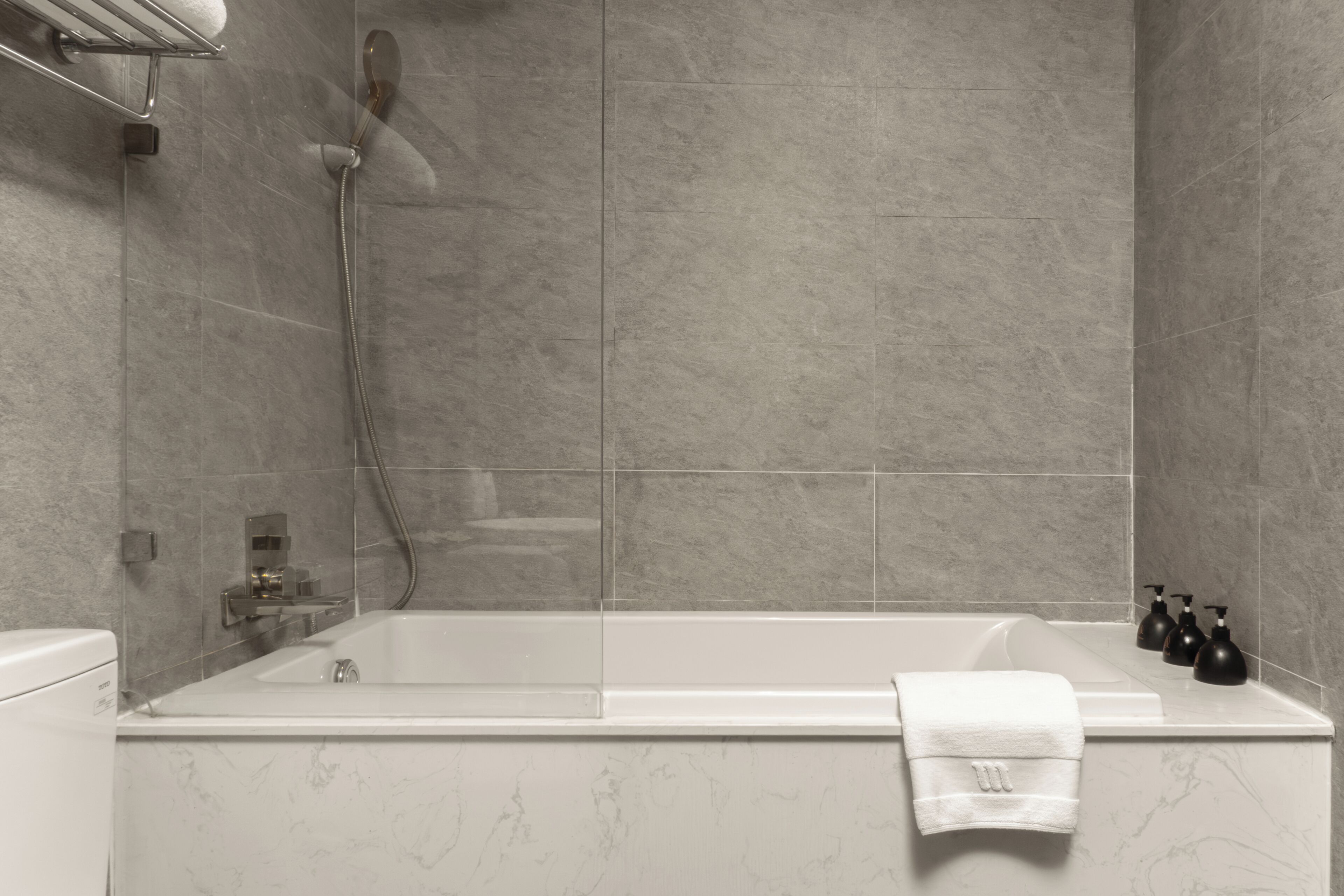 Un baño moderno con una bañera independiente, un cabezal de ducha manual y un juego de dispensadores de jabón negros.