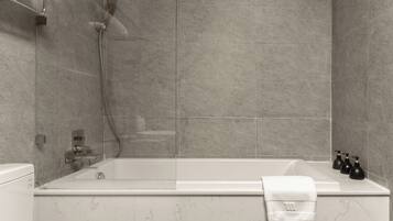 Un baño moderno con una bañera independiente, un cabezal de ducha manual y un juego de dispensadores de jabón negros.
