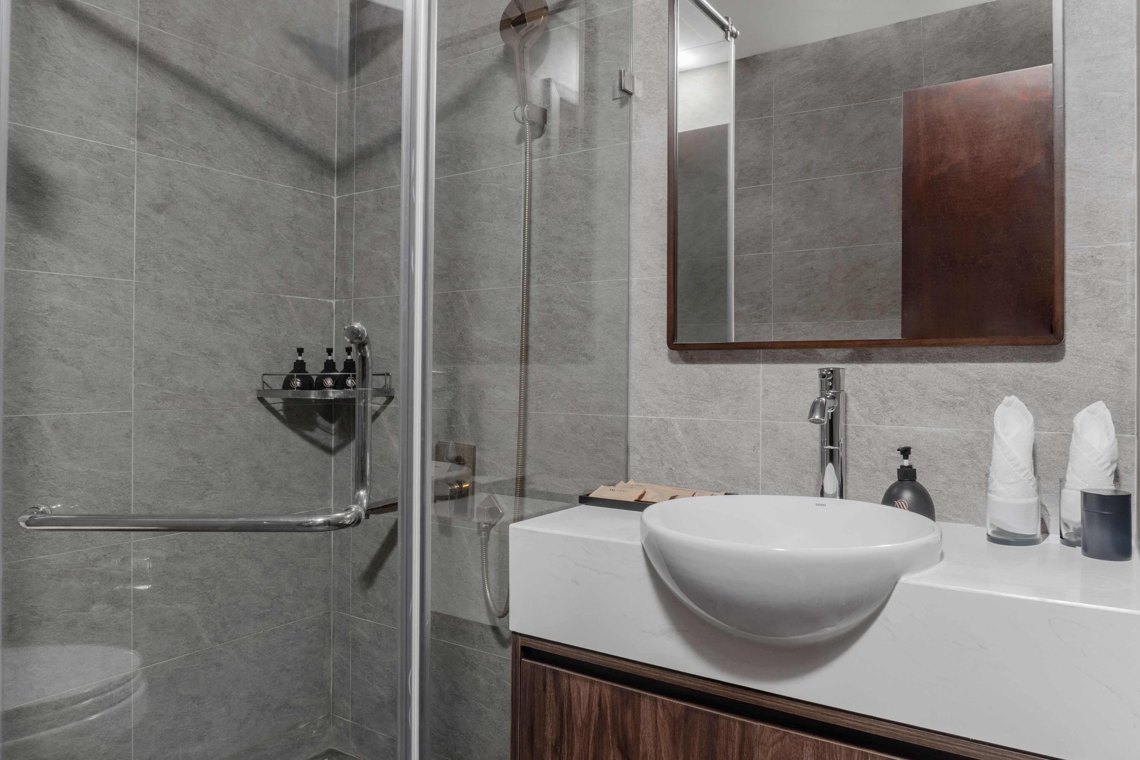Un baño moderno con cabina de ducha de vidrio, un lavamanos blanco y un espejo grande.
