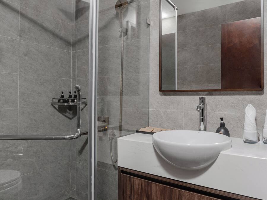 Un baño moderno con cabina de ducha de vidrio, un lavamanos blanco y un espejo grande.