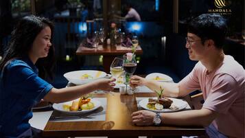 A dining table with plates of food, glasses, and a rose garnish.