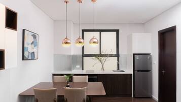 Eine moderne Küche mit Esstisch, Stühlen, Pendelleuchten, einem Kühlschrank und einem Fenster mit Blick.