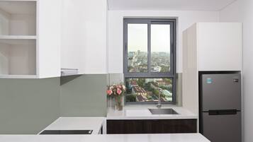 A modern kitchen with a built-in refrigerator, a window with a view of a cityscape, and a vase with flowers on the counter.