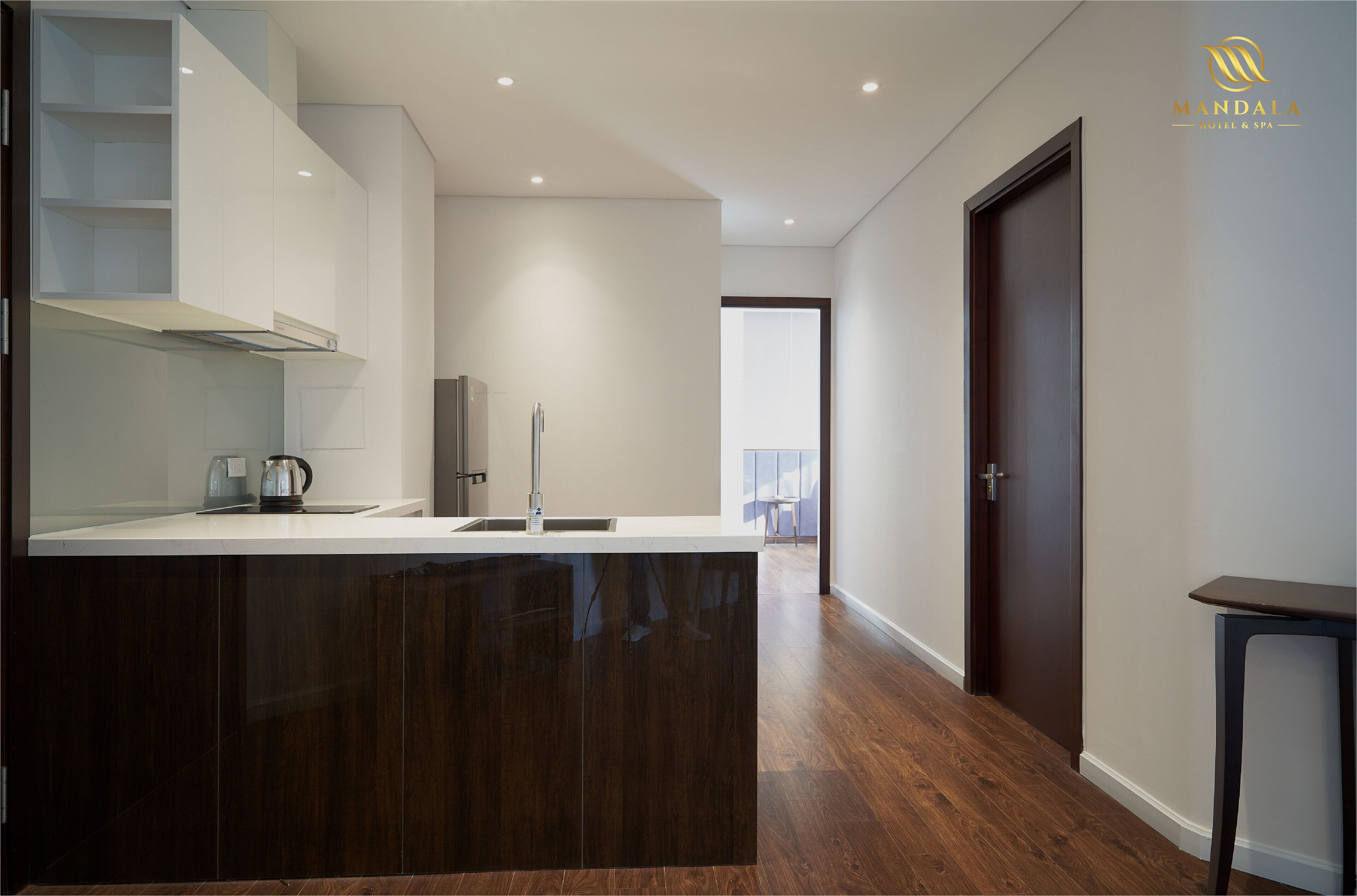 A modern kitchen with dark cabinetry, a white countertop, and a stainless steel sink.