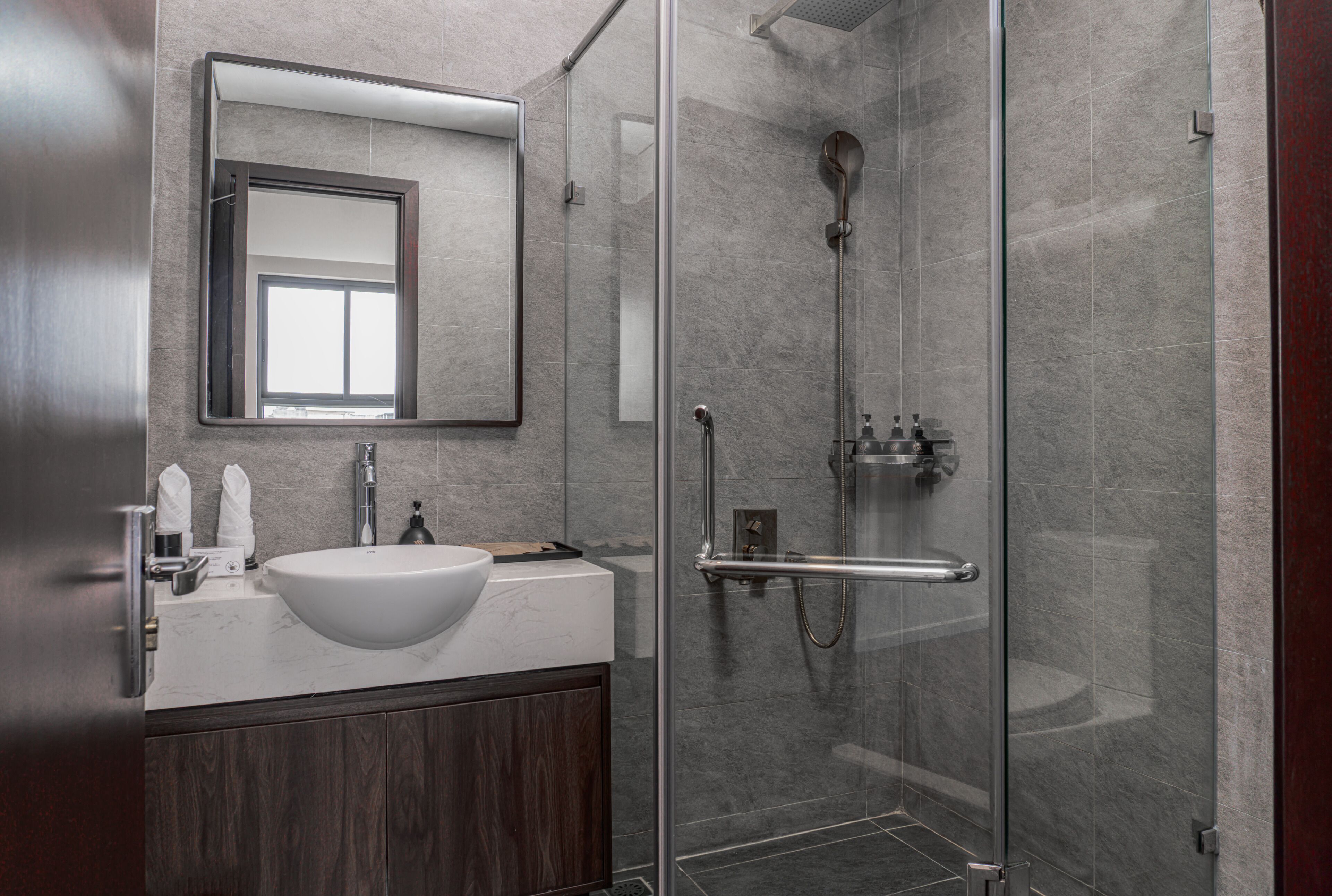 Un bagno moderno con doccia vetrata, un lavandino bianco e uno specchio grande sopra il mobile.