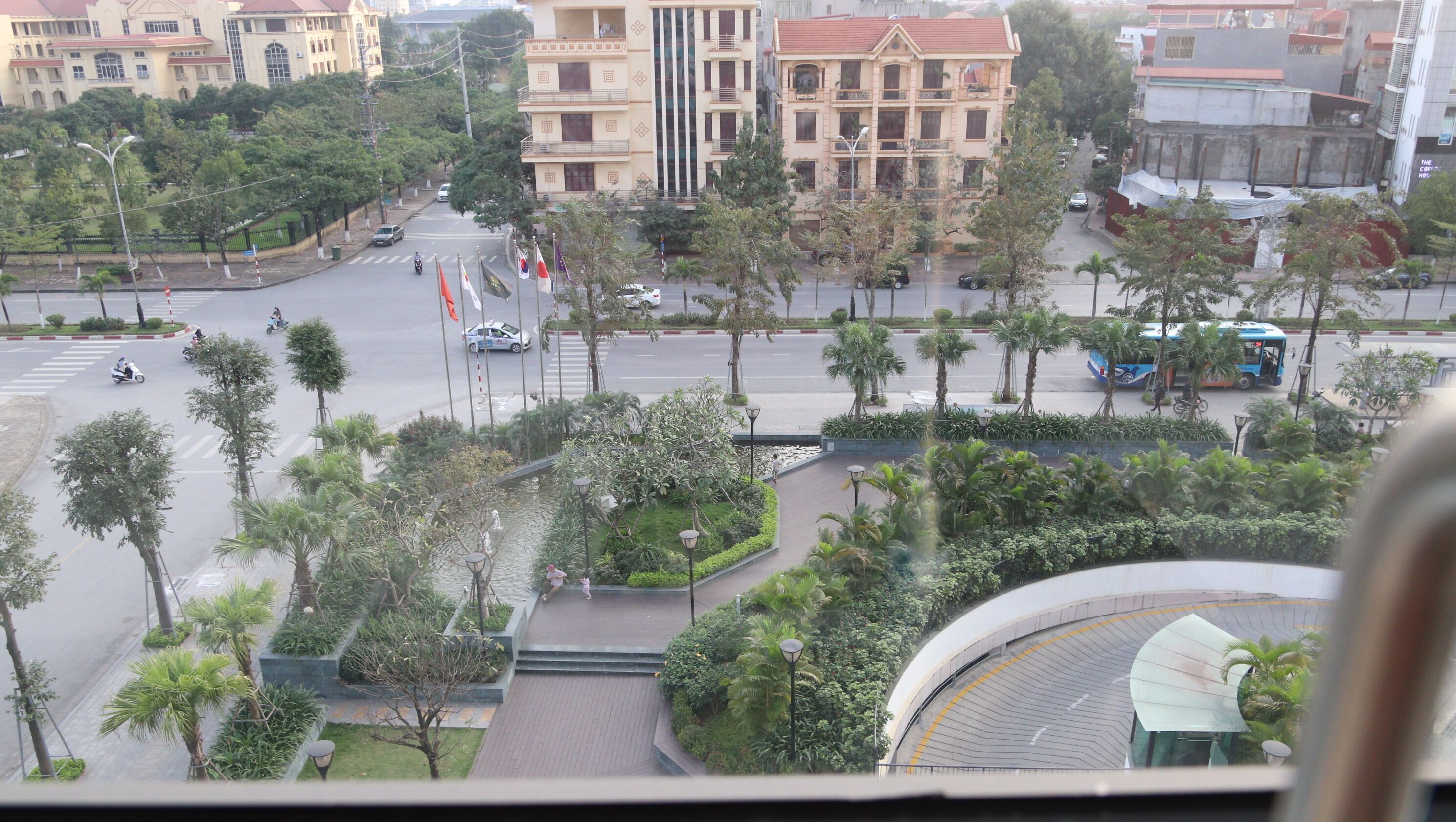 A view of a city intersection with buildings, trees, and a pedestrian walkway.