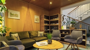 A cozy living room with a green sofa, two armchairs, a coffee table, and a bookshelf. - Stadthotel Pfeffermuhle (Gengenbach)