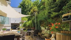 An outdoor patio with a table and chairs, surrounded by potted plants and a statue. - Stadthotel Pfeffermuhle (Gengenbach)