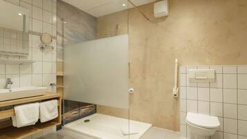 Un baño moderno con ducha de vidrio, lavamanos blanco y un inodoro.