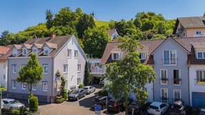A residential street with houses, parked cars, and a church in the background. - Stadthotel Pfeffermuhle (Gengenbach)