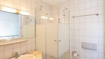 Ein modernes Badezimmer mit einer Duschkabine, einem Waschbecken mit Granitablage und einer Toilette.