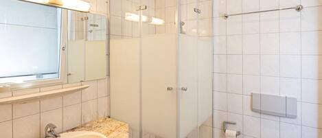 Un bagno moderno con cabina doccia in vetro, lavabo con piano in granito e servizi igienici.