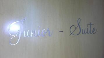 Un letrero con el texto 'Junior - Suite' sobre un fondo liso.