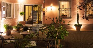 An outdoor patio area with a table and chairs, potted plants, and a staircase leading to an entrance. - Hotel Morgensonne (Badenweiler)