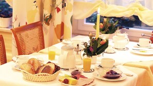 A breakfast setting with a table set for two, including bread, fruit, and tea. - Hotel Morgensonne (Badenweiler)