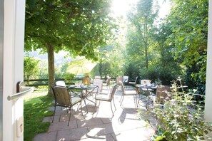 An outdoor patio with tables and chairs, surrounded by greenery and a fence. - Hotel Morgensonne (Badenweiler)