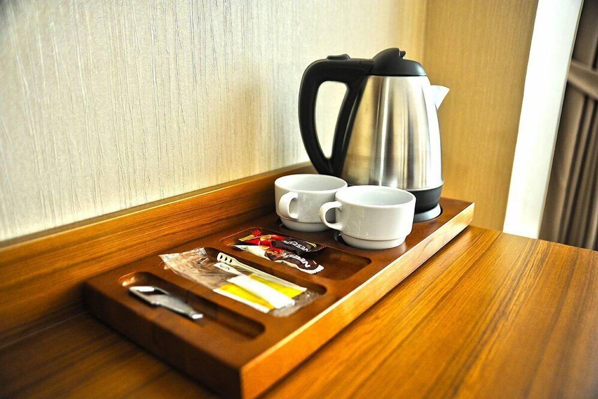 A wooden tray with a coffee maker, two white cups, and a tray with a knife, spoon, and condiments.
