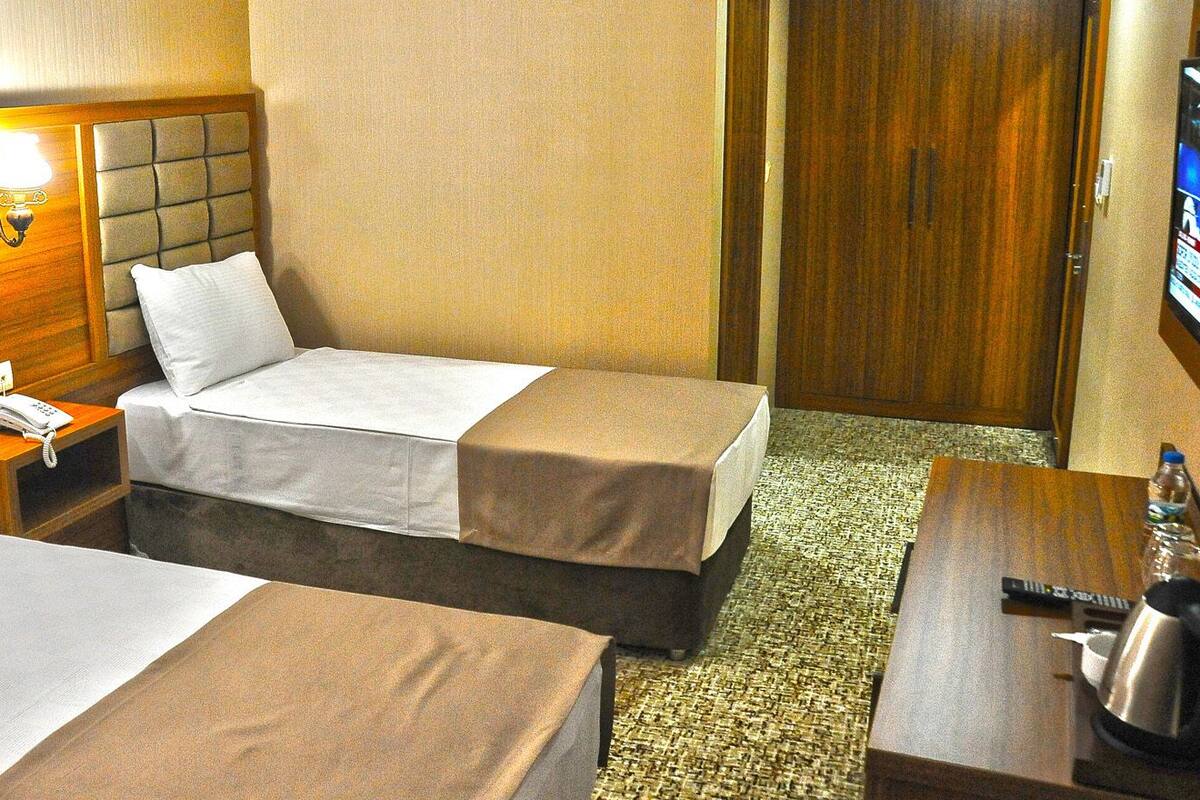 A hotel room with two beds, a bedside table with a phone, a TV on the wall, and a coffee maker on a side table.
