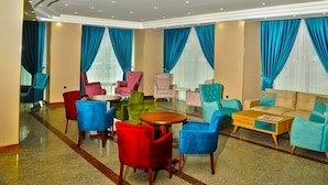 A hotel lobby with multiple seating areas, including chairs and sofas, arranged around a central coffee table. - Aksehir Elitt Hotel (Aksehir)