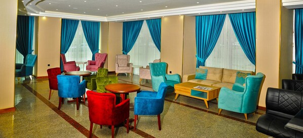 A hotel lobby with multiple seating areas, including chairs and sofas, arranged around a central coffee table.