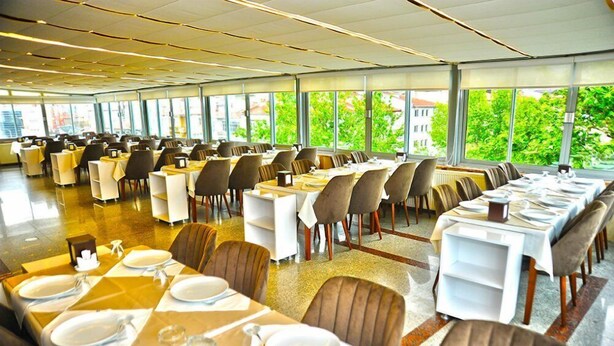 A spacious dining area with multiple tables and chairs, large windows offering a view of greenery outside. - Aksehir Elitt Hotel (Aksehir)