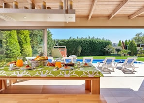 Un área de comedor con una mesa lista para el desayuno, con vista a una piscina y un jardín exuberante.