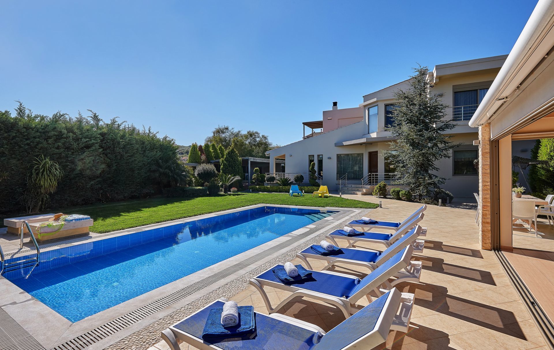 A swimming pool with lounge chairs, a well-maintained lawn, and a modern building in the background.