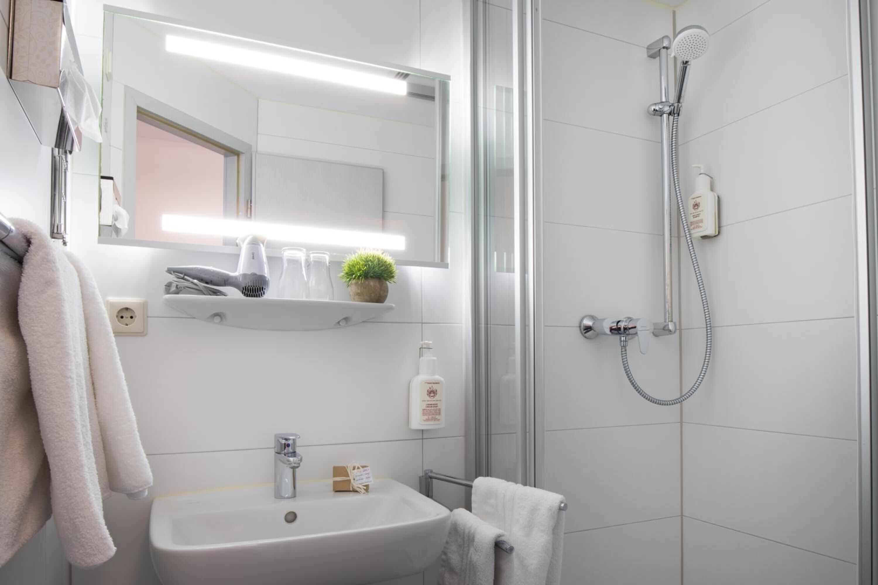 A modern bathroom with a sink, mirror, and shower.