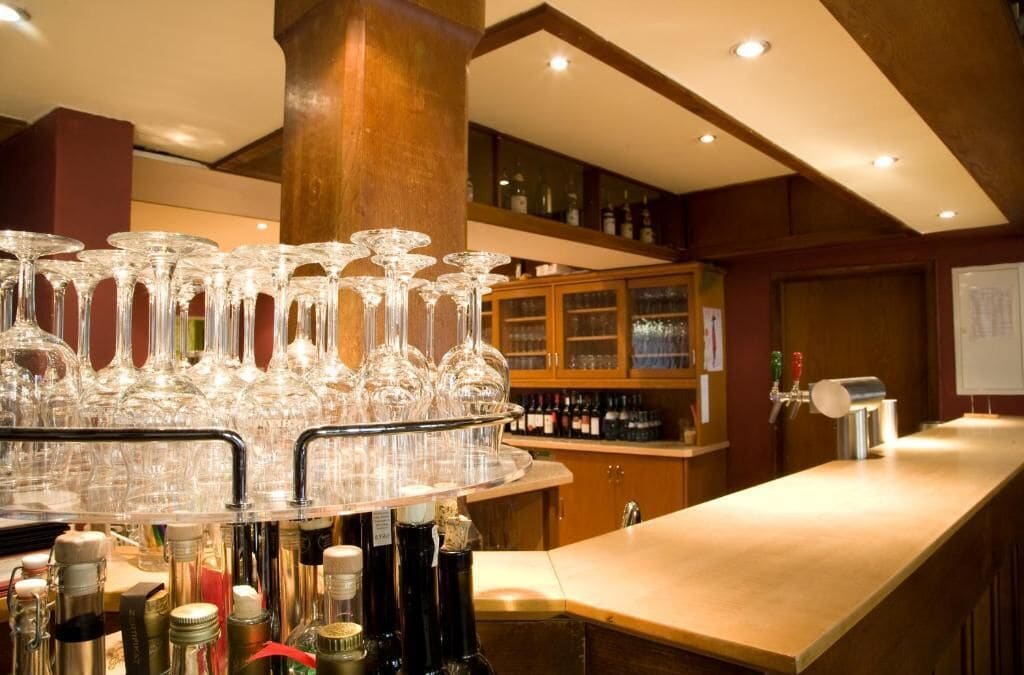 A bar area with a round bar counter, multiple wine glasses, and a variety of bottles.