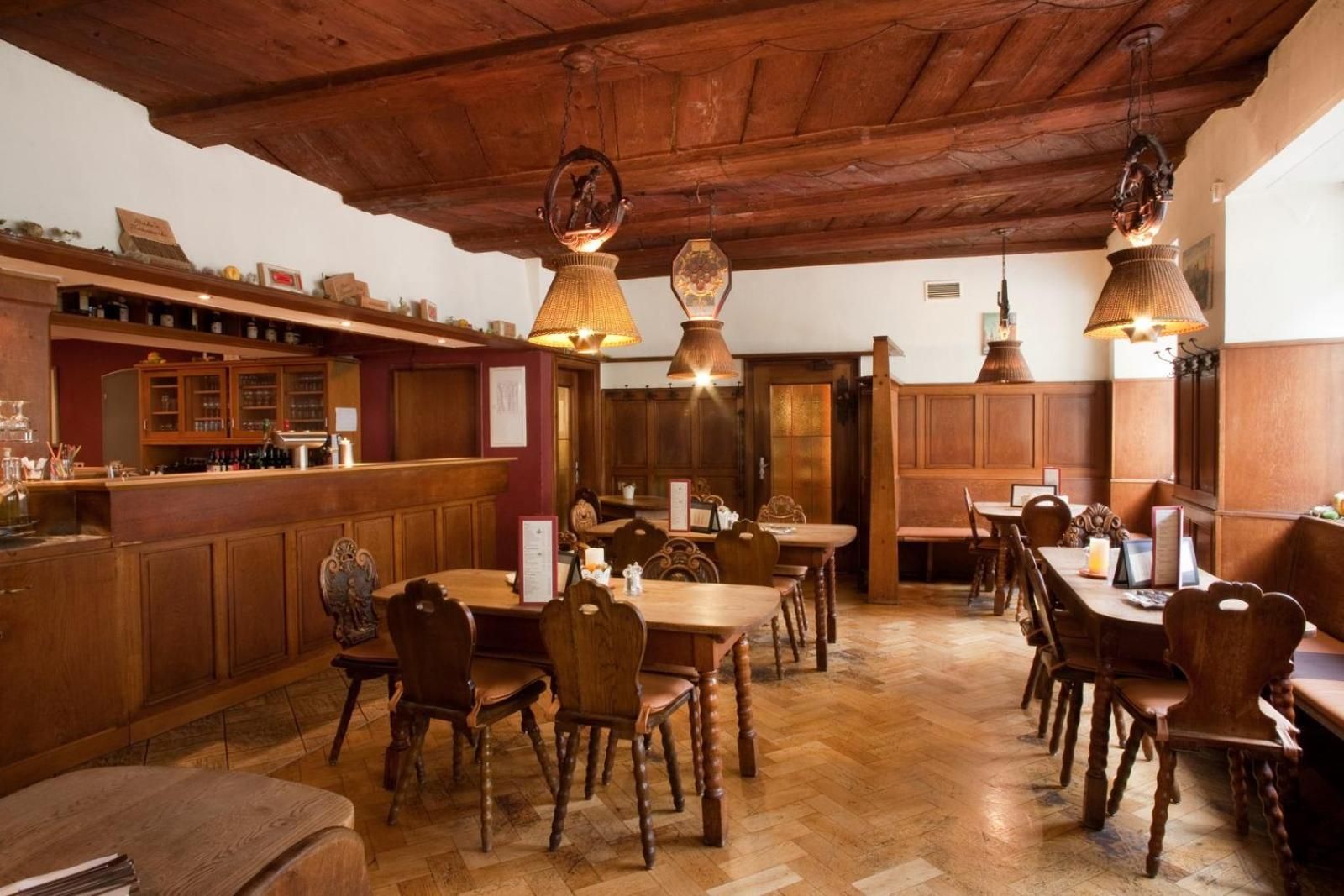 Un interior de restaurante con muebles de madera, lámparas colgantes y una zona de bar.