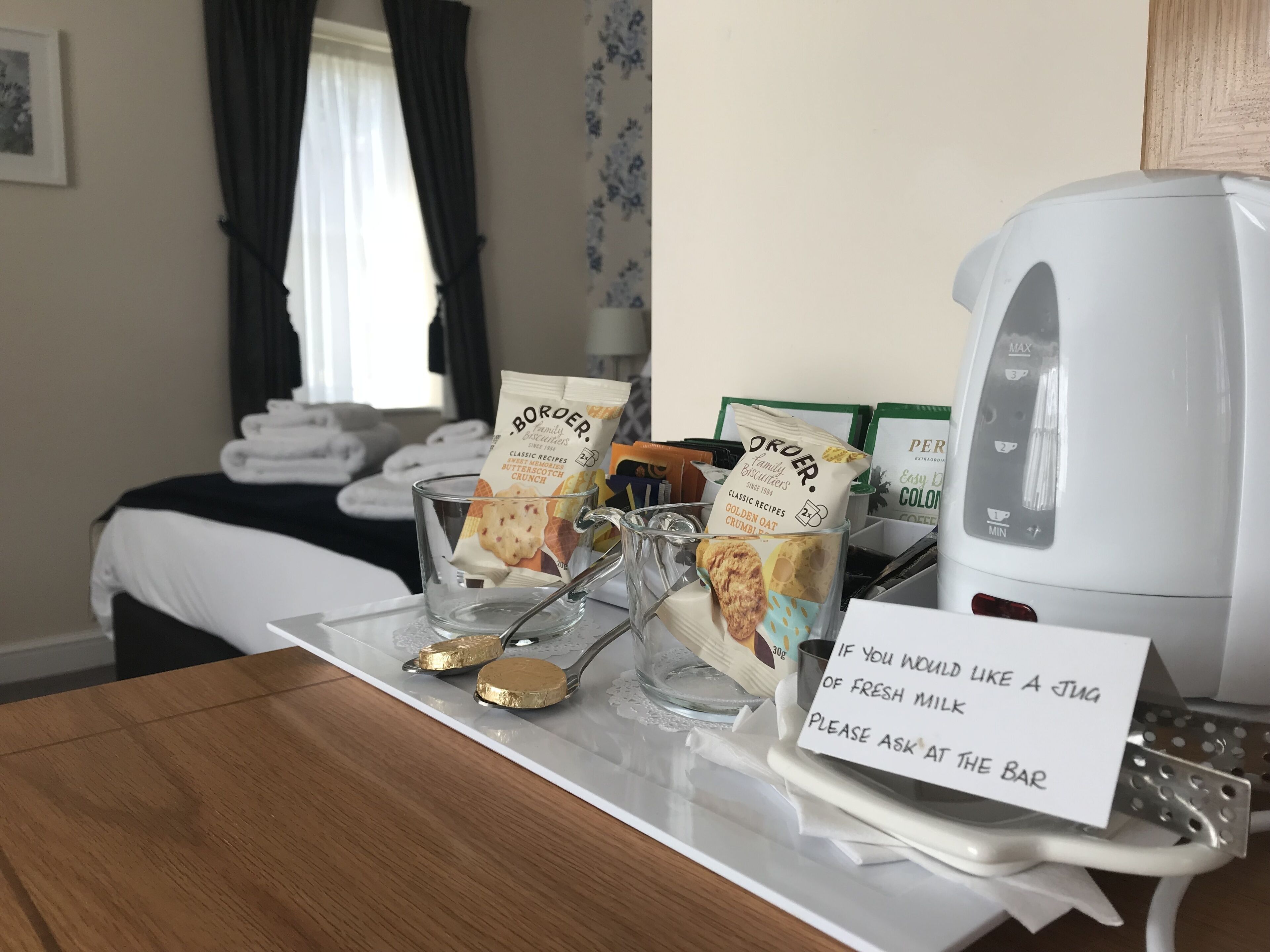 Et hotelværelse med et morgenmadssætholdende müsliblanding, en mælkekande og et skilt, der tilbyder frisk mælk i baren.